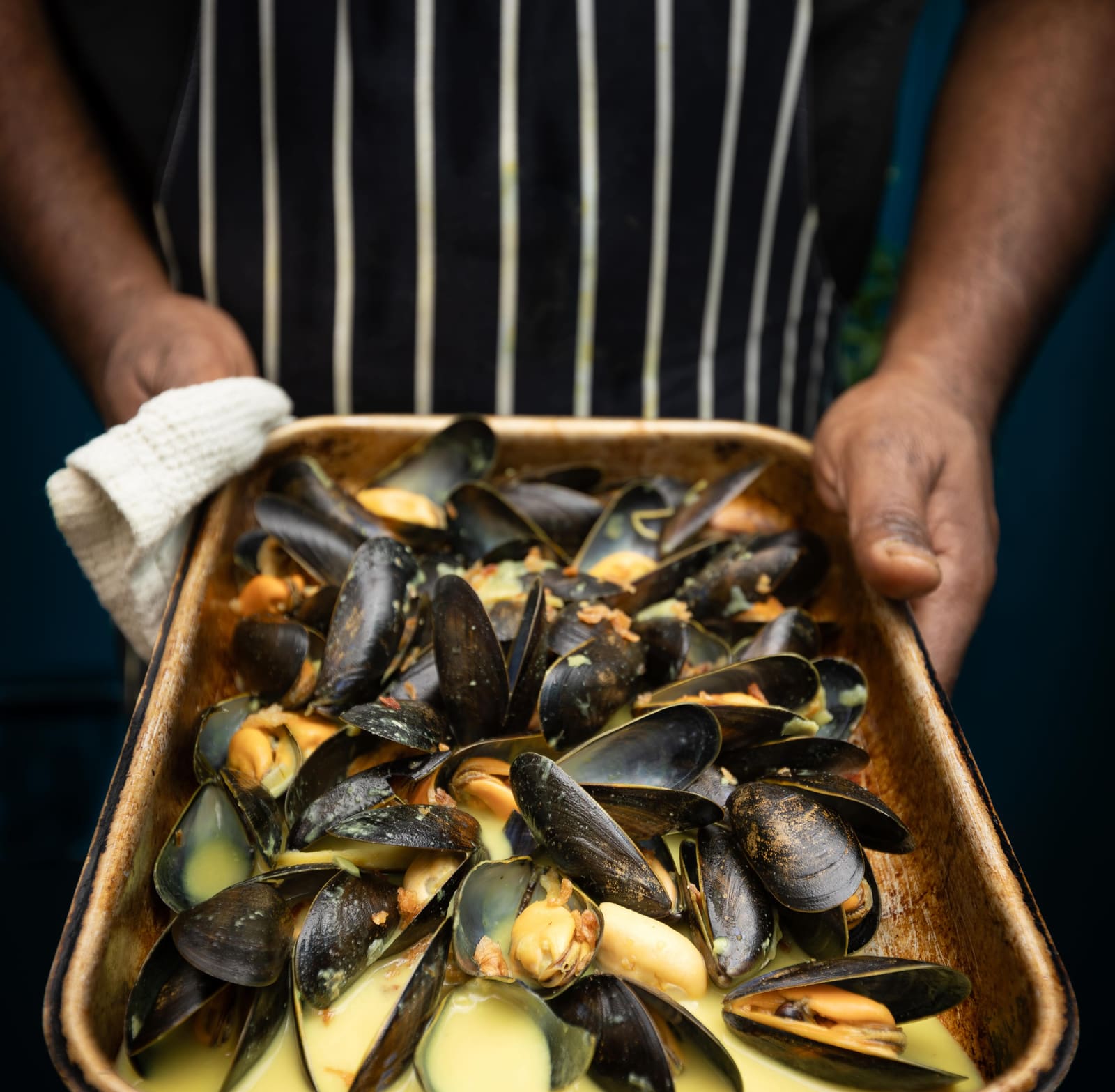 A tray of steamed mussels carried through the kitchen